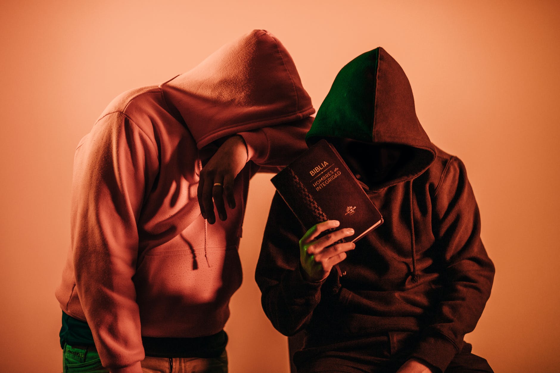 two person in pullover hoodies holding book